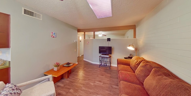 living room featuring a textured ceiling, ceiling fan, and brick wall