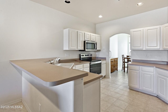 kitchen featuring kitchen peninsula, appliances with stainless steel finishes, white cabinetry, and sink