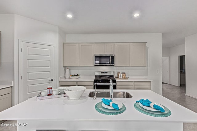 kitchen featuring gray cabinets, sink, stainless steel appliances, and a kitchen island with sink