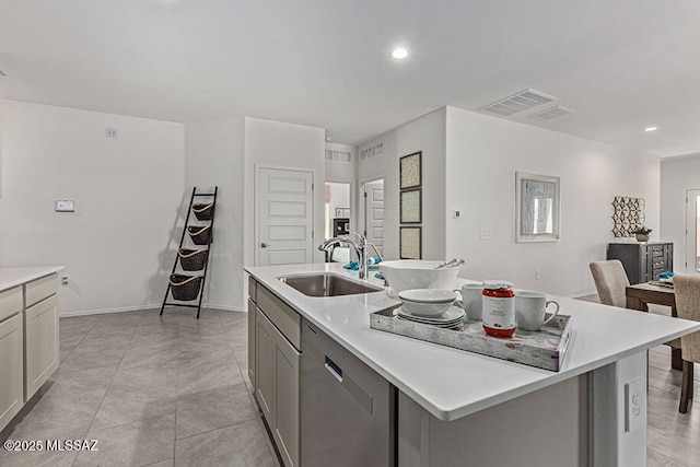 kitchen featuring stainless steel dishwasher, sink, gray cabinetry, and a kitchen island with sink