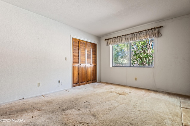 unfurnished bedroom with carpet flooring, a textured ceiling, and a closet