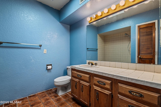 bathroom featuring tile patterned floors, vanity, toilet, and walk in shower