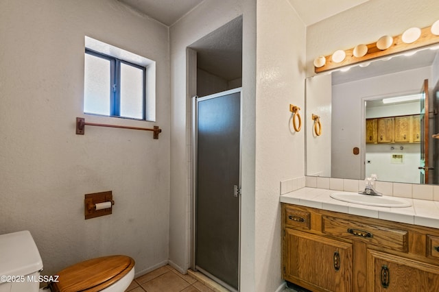 bathroom with tile patterned floors, vanity, toilet, and a shower with door