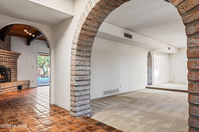 interior space with carpet flooring, a fireplace, and beamed ceiling