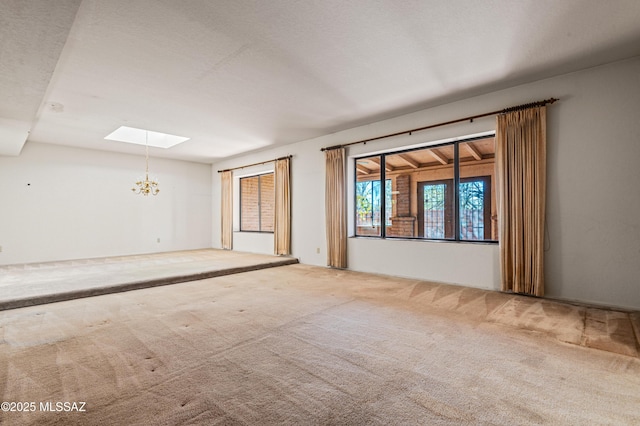 unfurnished room featuring a skylight, carpet floors, a textured ceiling, and an inviting chandelier