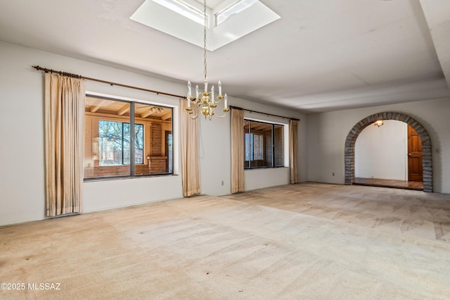 carpeted empty room with an inviting chandelier