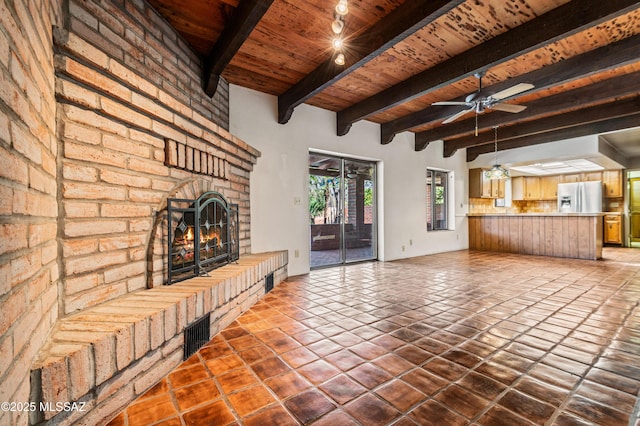 unfurnished living room with ceiling fan, beam ceiling, wooden ceiling, and a brick fireplace