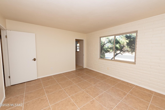 tiled empty room featuring brick wall