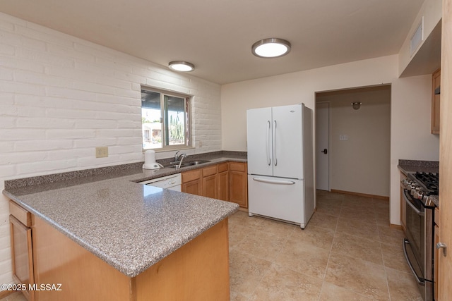 kitchen with sink, white appliances, kitchen peninsula, and brick wall