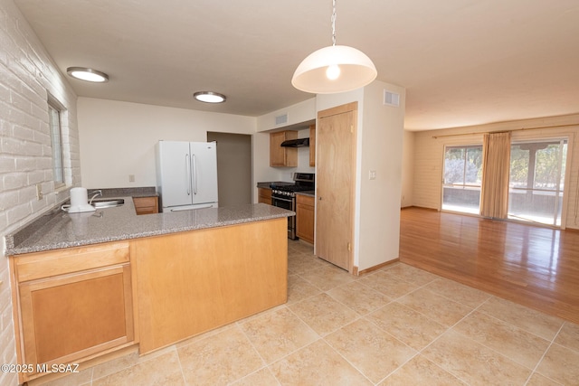 kitchen with kitchen peninsula, custom exhaust hood, pendant lighting, white fridge, and stainless steel range with gas stovetop