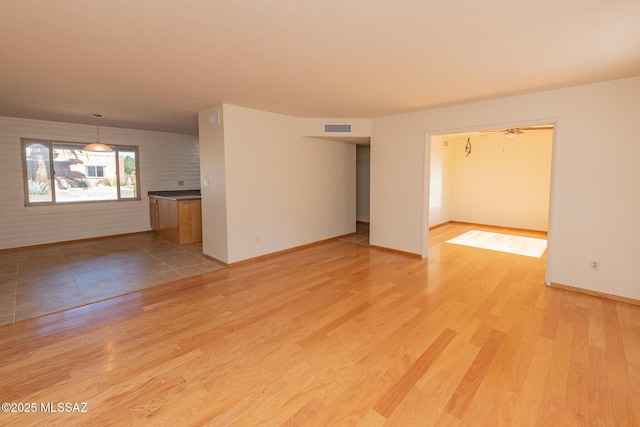 empty room featuring brick wall and light hardwood / wood-style flooring