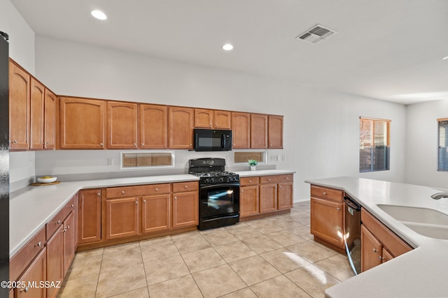 kitchen featuring sink, light tile patterned flooring, and black appliances