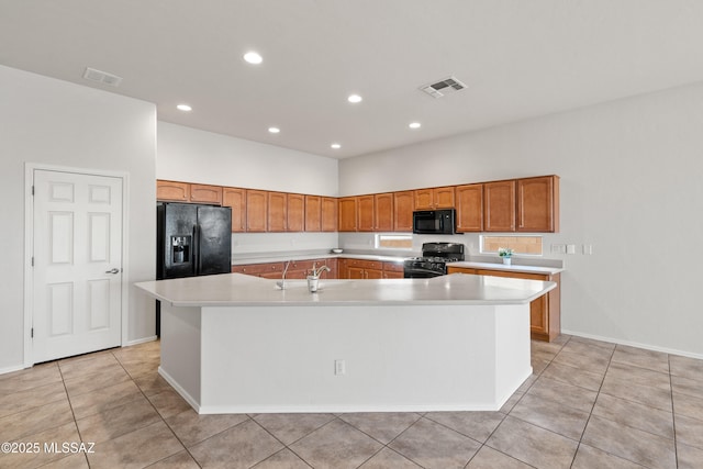 kitchen featuring light tile patterned floors, sink, a kitchen island with sink, and black appliances