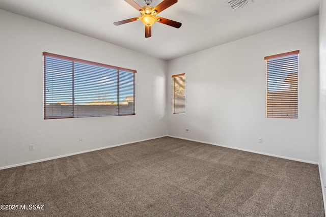 empty room featuring ceiling fan and dark carpet