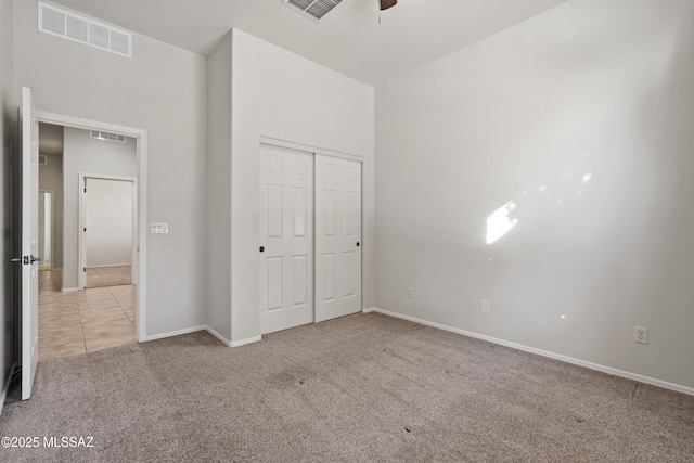 unfurnished bedroom featuring ceiling fan, a closet, and light carpet