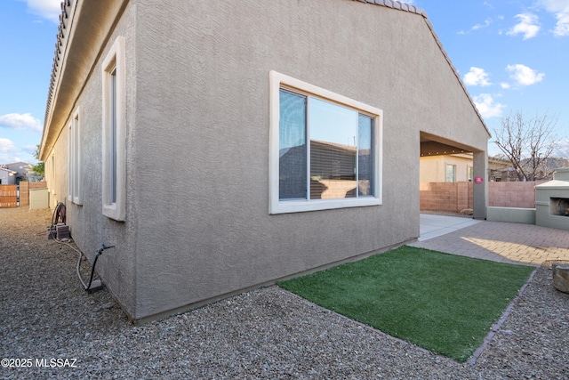 view of property exterior featuring a fireplace and a patio