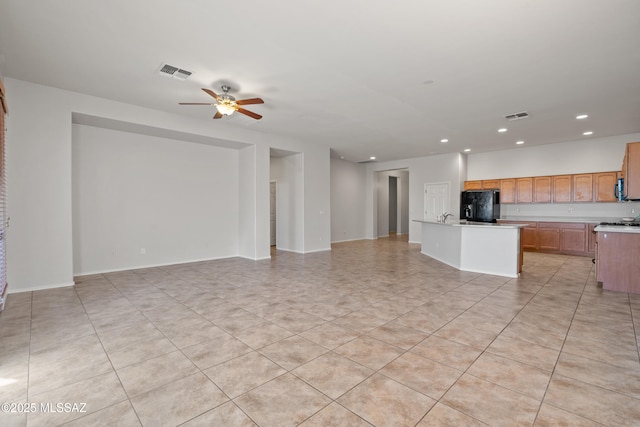 unfurnished living room featuring ceiling fan, light tile patterned floors, and sink