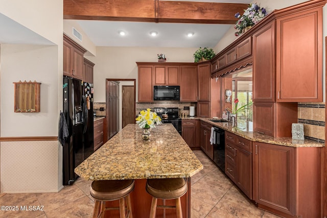 kitchen featuring light stone countertops, beam ceiling, tasteful backsplash, a kitchen island, and black appliances