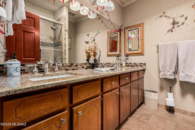 bathroom with a sink, tasteful backsplash, a shower stall, and double vanity