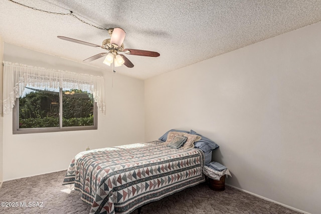 bedroom featuring a textured ceiling, dark colored carpet, and ceiling fan