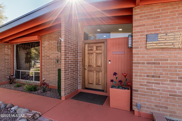 view of exterior entry featuring brick siding