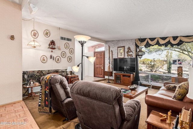 living room with a textured ceiling, wallpapered walls, and visible vents
