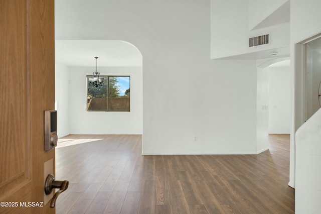 spare room with a chandelier and dark hardwood / wood-style floors