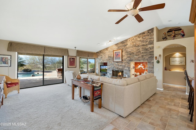 living room with ceiling fan, lofted ceiling, and a fireplace