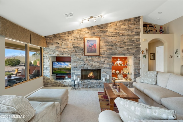 living room featuring lofted ceiling and a stone fireplace