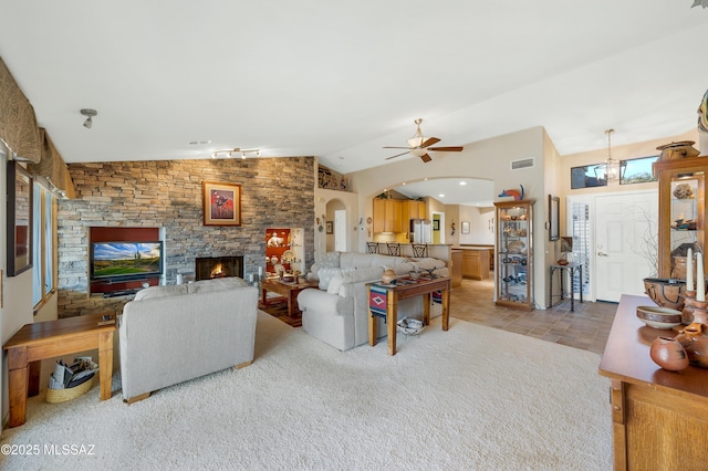 living room with a stone fireplace, vaulted ceiling, and ceiling fan