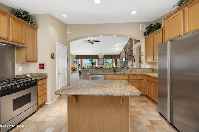 kitchen featuring sink, a breakfast bar area, appliances with stainless steel finishes, a center island, and kitchen peninsula