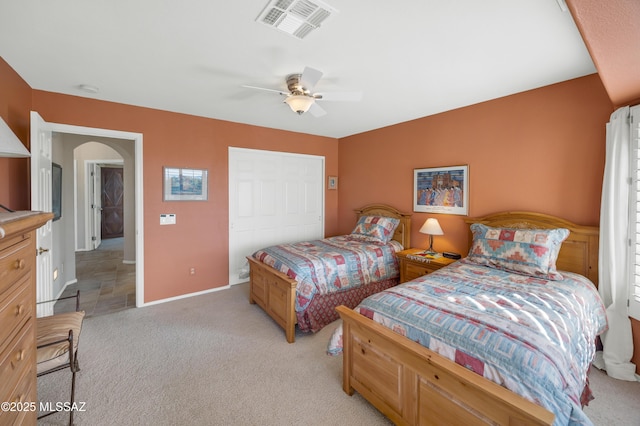 bedroom featuring light colored carpet, ceiling fan, and a closet