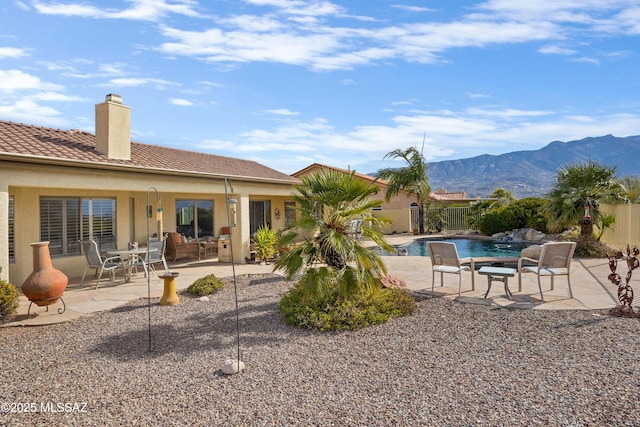 rear view of house with a fenced in pool, a mountain view, and a patio area