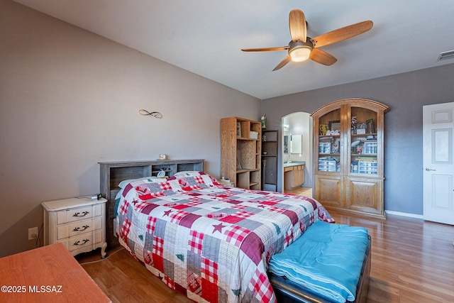 bedroom with ceiling fan, ensuite bathroom, and wood-type flooring