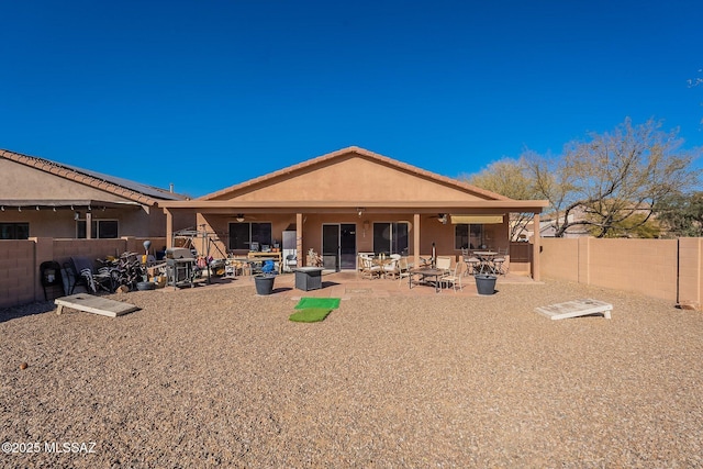 back of property with solar panels and a patio