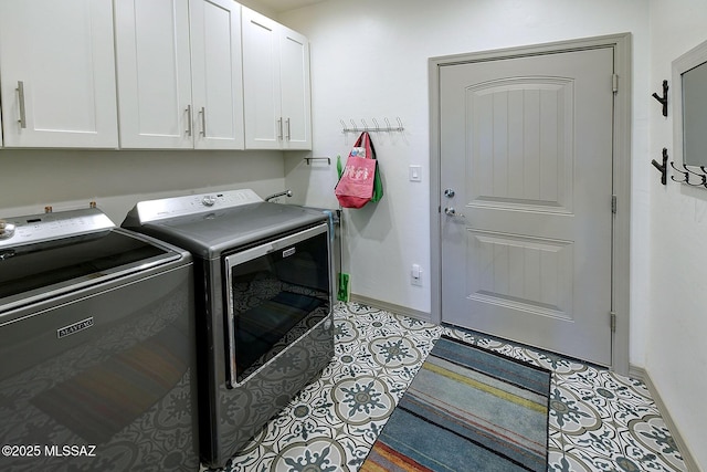 washroom featuring washing machine and dryer, light tile patterned flooring, and cabinets