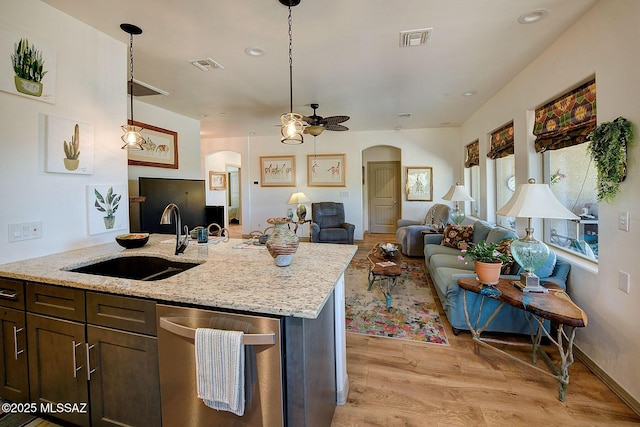 kitchen featuring ceiling fan, dishwasher, hanging light fixtures, light stone countertops, and sink