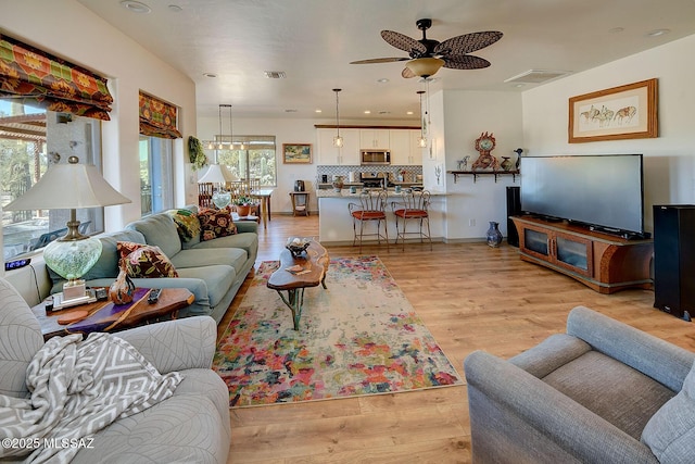 living room featuring light hardwood / wood-style floors, ceiling fan, and a healthy amount of sunlight