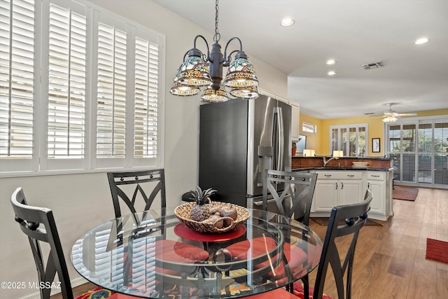 dining space featuring hardwood / wood-style floors and ceiling fan with notable chandelier