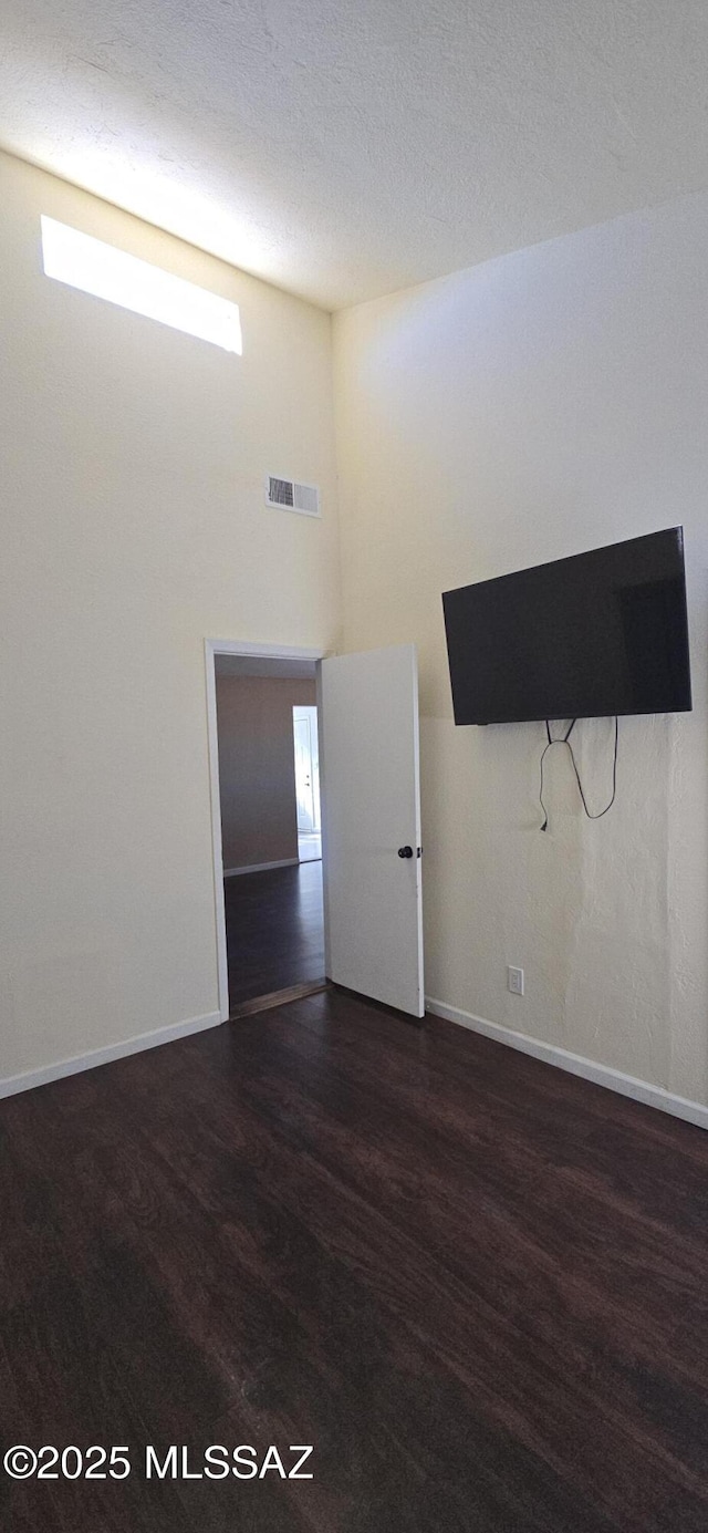 spare room featuring a high ceiling and dark hardwood / wood-style floors