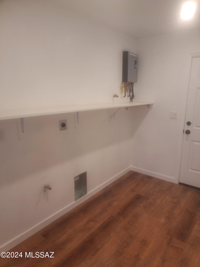 clothes washing area with dark hardwood / wood-style floors and tankless water heater