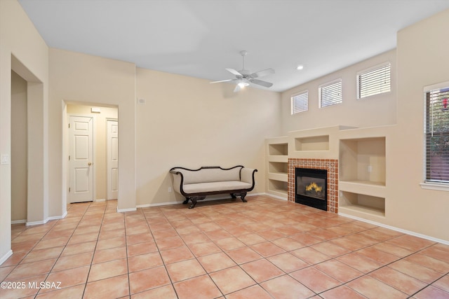 living area featuring a fireplace, built in shelves, ceiling fan, and light tile patterned flooring