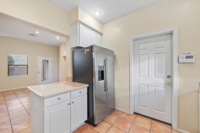 kitchen featuring kitchen peninsula, white cabinets, light tile patterned flooring, and stainless steel refrigerator with ice dispenser