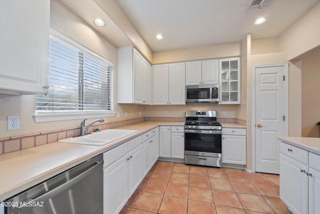 kitchen with sink, white cabinets, light tile patterned floors, and appliances with stainless steel finishes