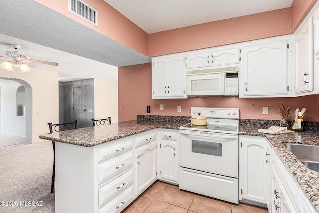 kitchen featuring white appliances, kitchen peninsula, ceiling fan, and white cabinetry