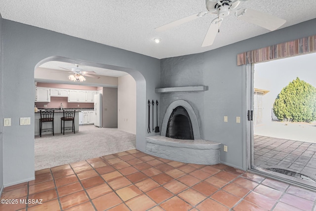 unfurnished living room with sink, carpet floors, a large fireplace, and a textured ceiling