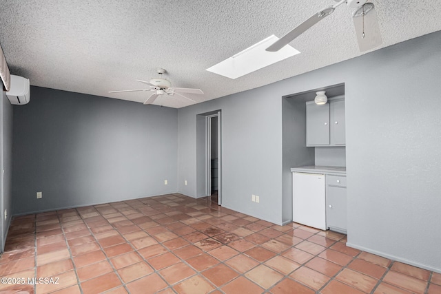 tiled spare room featuring a textured ceiling, ceiling fan, a skylight, and a wall mounted air conditioner