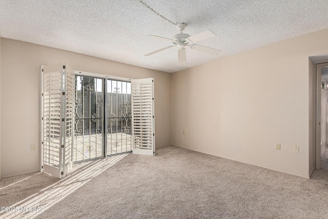 spare room with a textured ceiling, ceiling fan, and carpet