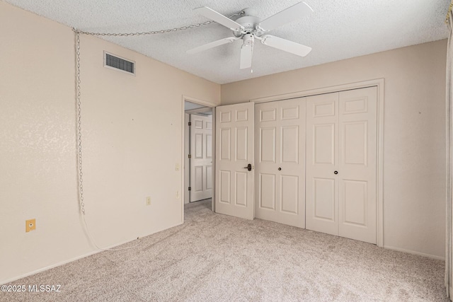 unfurnished bedroom featuring a textured ceiling, light colored carpet, ceiling fan, and a closet