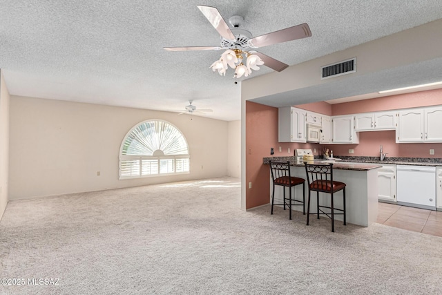 kitchen with white cabinetry, white appliances, ceiling fan, light carpet, and a breakfast bar area